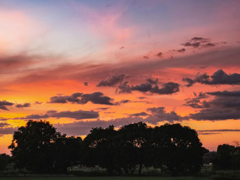 Silhouette trees by lake against romantic sky at sunset