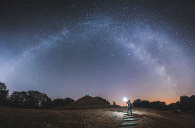 Man holding flashlight on land against sky