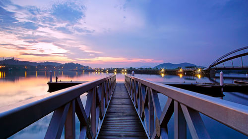 Footbridge over sea against sky during sunset