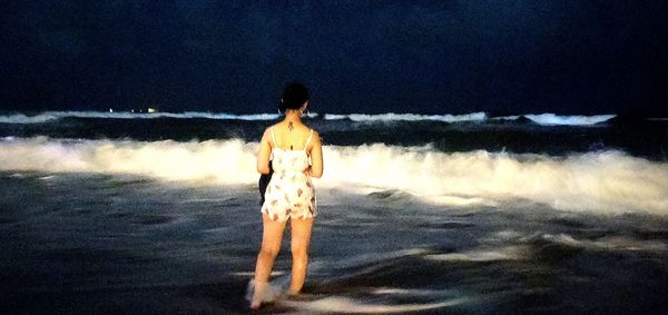 Rear view of woman standing on beach