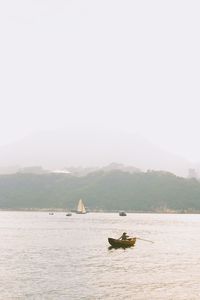 Boat sailing on sea against clear sky