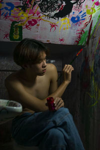 Young man holding a paintbrush and aiming at the wall