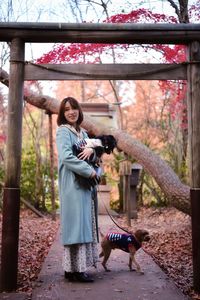 Portrait of young woman photographing while standing in park with dog