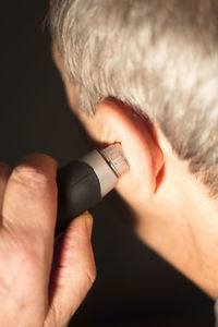 Close-up of man holding electric razor to ear