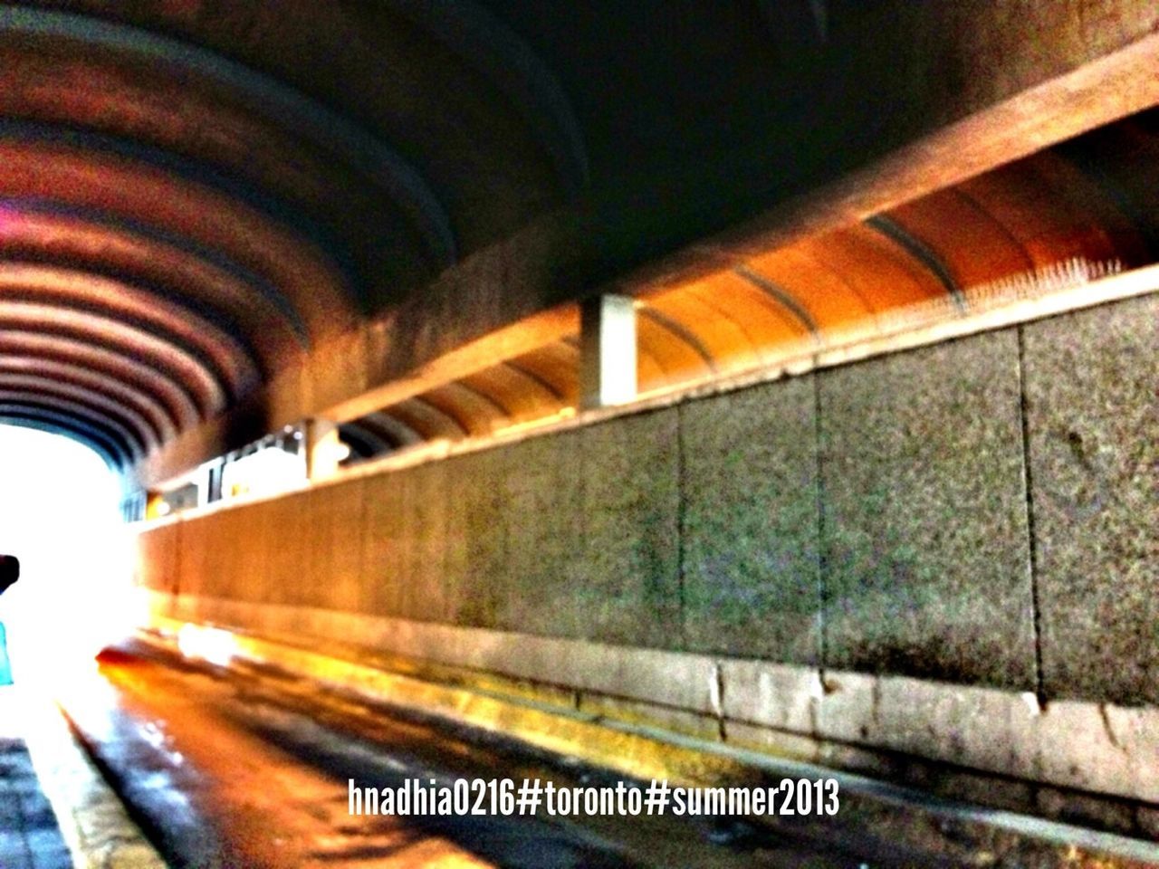 indoors, transportation, architecture, built structure, rail transportation, public transportation, railroad station, railroad track, the way forward, railing, railroad station platform, subway station, architectural column, bridge - man made structure, illuminated, connection, tunnel, text, diminishing perspective, wall - building feature