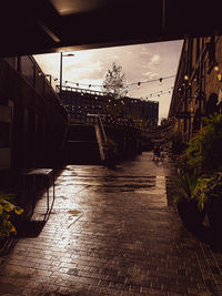 Wet footpath amidst buildings in city