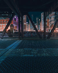 Illuminated bridge by buildings against sky at night