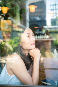 Portrait of a young woman sitting on table at restaurant