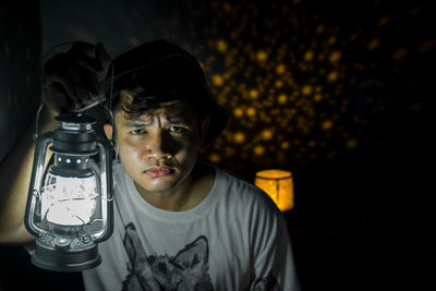 Portrait of young man holding lantern at night