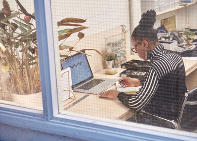 High angle view of businesswoman seen through window working at office