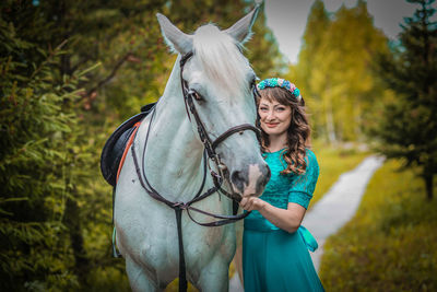 Portrait of smiling young woman standing by horse
