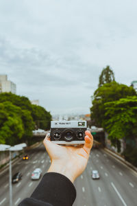 Man photographing car on road against sky