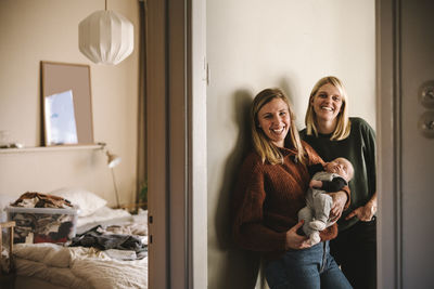 Portrait of smiling mothers holding newborn baby