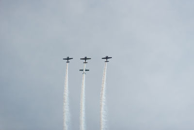 Low angle view of airplanes flying against sky during air show