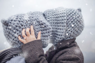 Girl in knitted grey hat hugging her frozen smaller brother