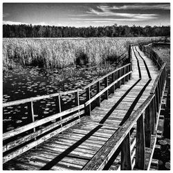 Footbridge over lake against sky