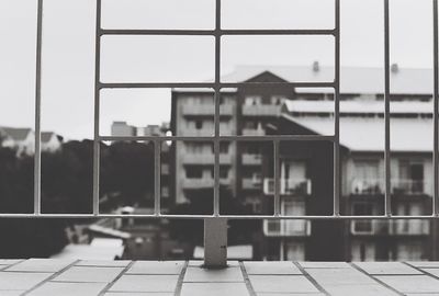Close-up of railing by buildings against sky
