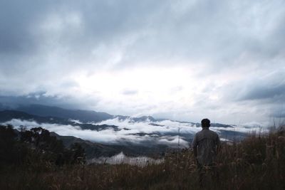 Rear view of man standing by sea against sky