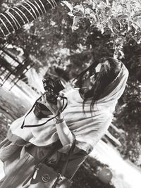 Rear view of woman with umbrella against trees