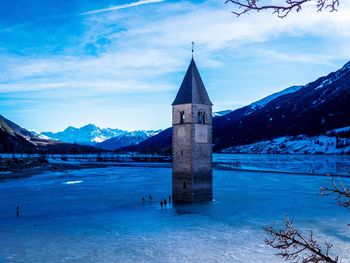 Gazebo by building against sky during winter