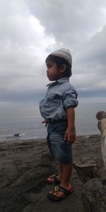 Full length of boy standing on beach against sky