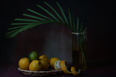 Still life with yellow and green citrus lemon fruits on table against black background