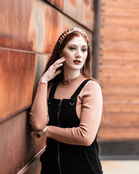 Portrait of young woman standing against wall