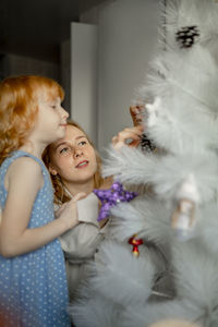 Mother and daughter decorating christmas tree at home