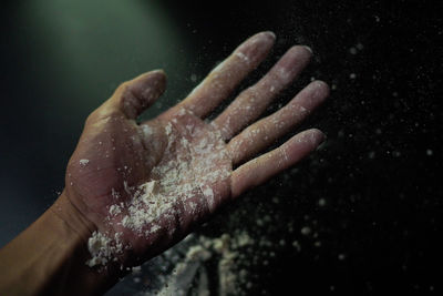 Close-up of hand holding leaf against black background