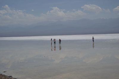 People at beach against sky