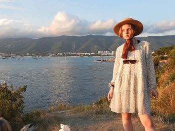 Portrait of woman standing against lake