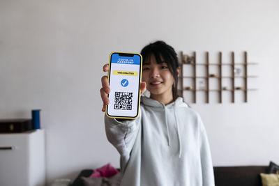 Young woman holding mobile phone with vaccination qr code on screen