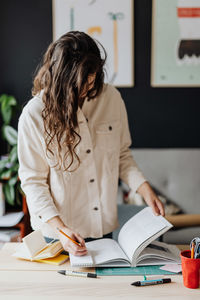 Woman writing on diary at desk in office