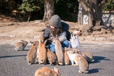 Smiling mid adult woman feeding rabbit on road