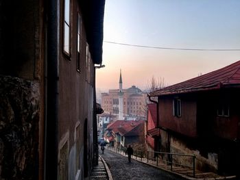 Street amidst houses against sky at sunset