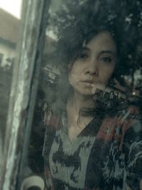 Portrait of young woman looking through tree