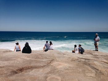 People sitting on beach against clear sky