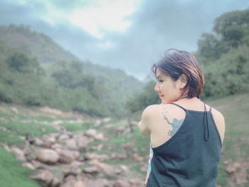 Young woman looking away while standing on land