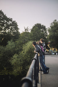 Male and female teenage friends leaning on bridge railing
