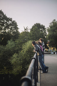 Male and female teenage friends leaning on bridge railing