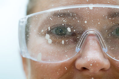 Close up of a woman face wearing protective glasses covered in paint