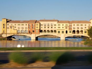 Bridge over river in city against clear sky