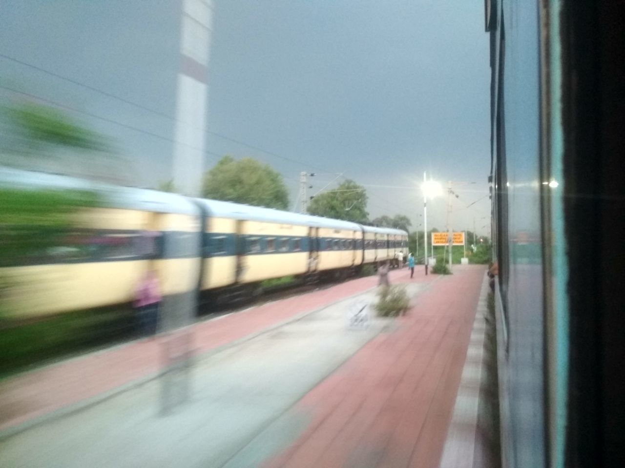 BLURRED MOTION OF TRAIN AT RAILROAD STATION PLATFORM AGAINST SKY