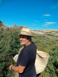 Man looking over shoulder while wearing hat by plants on field