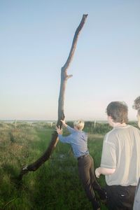Men standing on field against clear sky