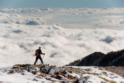 Man skiing on snowcapped mountain against sky