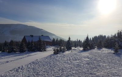 Snow covered landscape against sky during sunny day