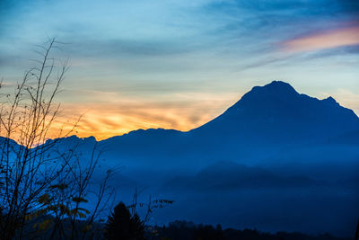 Scenic view of dramatic sky over silhouette mountains