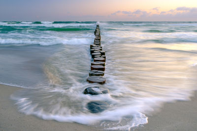 Wooden posts at beach against sky