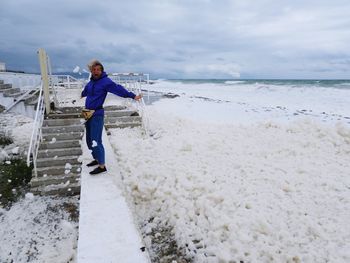 Full length of women on beach with sea foam